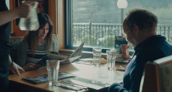 Movie still from “Private Life” (2018), directed by Tamara Jenkins – Two people are sitting at a table reading a newspaper; Medium shot, Over the shoulder angle