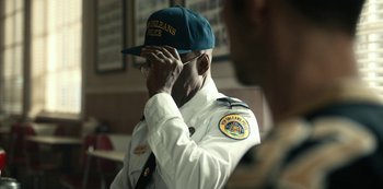 Movie still from “Project Power” (2020), directed by Henry Joost – A police officer adjusts his cap while wearing his uniform; Close Up shot, Over the shoulder angle
