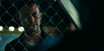 Movie still from “Project Power” (2020), directed by Henry Joost – A person behind a chain link fence; Close Up shot, Over the shoulder angle