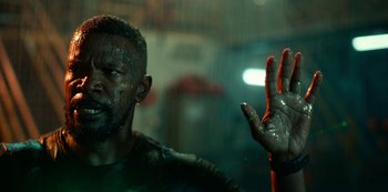 Movie still from “Project Power” (2020), directed by Henry Joost – A man in a green shirt is holding his hand up in the rain; Close Up shot, Low angle