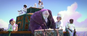 Movie still from “Puss in Boots: The Last Wish” (2022), directed by Januel Mercado – A man in a purple suit sitting on top of a box; Wide shot, Low angle