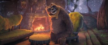 Movie still from “Puss in Boots: The Last Wish” (2022), directed by Januel Mercado – A brown bear sitting in front of a fire place; Wide shot, Over the shoulder angle