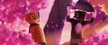 Movie still from “Puss in Boots: The Last Wish” (2022), directed by Januel Mercado – A cat and a person standing next to each other in front of trees; Medium shot, Over the shoulder angle