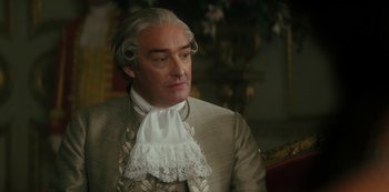 Movie still from “Queen Charlotte: A Bridgerton Story” (2023), directed by Tom Verica – An older man in a suit with a white collar; Close Up shot, Over the shoulder angle