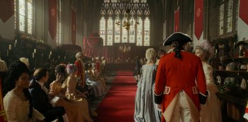 Movie still from “Queen Charlotte: A Bridgerton Story” (2023), directed by Tom Verica – A group of people dressed in period costumes in a church; Wide shot, Over the shoulder angle