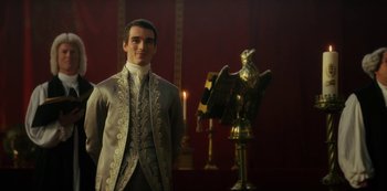 Movie still from “Queen Charlotte: A Bridgerton Story” (2023), directed by Tom Verica – A man standing in front of an eagle on a pedestal; Medium shot, Low angle