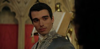 Movie still from “Queen Charlotte: A Bridgerton Story” (2023), directed by Tom Verica – A young man in a suit and tie standing in front of a painting; Close Up shot, Over the shoulder angle