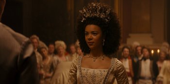 Movie still from “Queen Charlotte: A Bridgerton Story” (2023), directed by Tom Verica – A woman in a dress with a tiara in front of a group of people; Close Up shot, Low angle