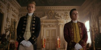 Movie still from “Queen Charlotte: A Bridgerton Story” (2023), directed by Tom Verica – Two men standing next to each other in front of a door way; Medium shot, Low angle