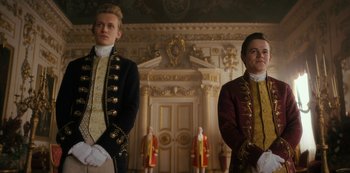 Movie still from “Queen Charlotte: A Bridgerton Story” (2023), directed by Tom Verica – Two men standing next to each other in front of a wall; Medium shot, Low angle