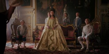 Movie still from “Queen Charlotte: A Bridgerton Story” (2023), directed by Tom Verica – A woman in a long dress standing in front of a group of people; Wide shot, High angle