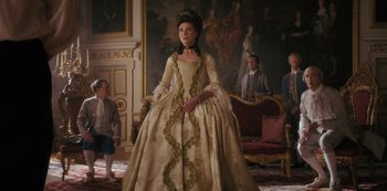 Movie still from “Queen Charlotte: A Bridgerton Story” (2023), directed by Tom Verica – A woman in a long dress in front of a group of people; Medium shot, Low angle