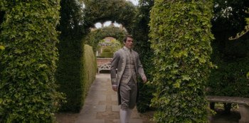 Movie still from “Queen Charlotte: A Bridgerton Story” (2023), directed by Tom Verica – A man in a suit walking through a garden; Wide shot, High angle
