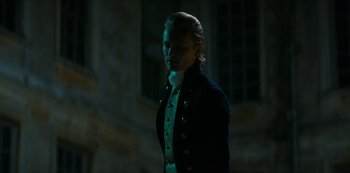 Movie still from “Queen Charlotte: A Bridgerton Story” (2023), directed by Tom Verica – A man in a black jacket standing in the dark; Medium shot, Low angle