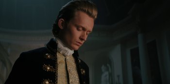 Movie still from “Queen Charlotte: A Bridgerton Story” (2023), directed by Tom Verica – A man in a black and gold jacket is looking down at his face; Close Up shot, Low angle