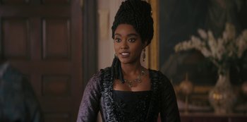 Movie still from “Queen Charlotte: A Bridgerton Story” (2023), directed by Tom Verica – A woman in a black dress and a black hat; Close Up shot, Over the shoulder angle