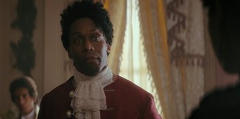 Movie still from “Queen Charlotte: A Bridgerton Story” (2023), directed by Tom Verica – A man in a red and white jacket and a white lace shirt; Close Up shot, Over the shoulder angle