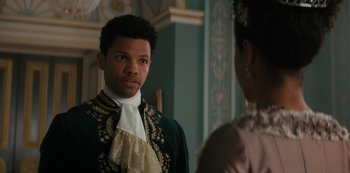 Movie still from “Queen Charlotte: A Bridgerton Story” (2023), directed by Tom Verica – A man wearing a suit and tie standing in front of a woman; Close Up shot, Over the shoulder angle