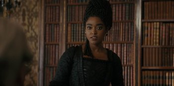 Movie still from “Queen Charlotte: A Bridgerton Story” (2023), directed by Tom Verica – A woman in a black dress standing in front of bookcases; Close Up shot, Low angle