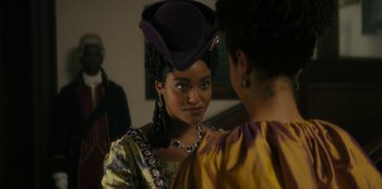 Movie still from “Queen Charlotte: A Bridgerton Story” (2023), directed by Tom Verica – A woman wearing a purple hat and a yellow dress; Close Up shot, Over the shoulder angle