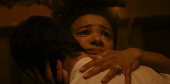 A young woman hugging another young woman with her hands on her chest