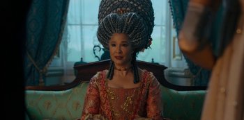 Movie still from “Queen Charlotte: A Bridgerton Story” (2023), directed by Tom Verica – A woman in a wig sitting on a couch; Medium shot, Over the shoulder angle