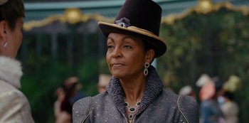 Movie still from “Queen Charlotte: A Bridgerton Story” (2023), directed by Tom Verica – An older woman wearing a black hat and a gray jacket; Close Up shot, Over the shoulder angle