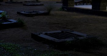Movie still from “RRR” (2022), directed by S.S. Rajamouli – An empty grave yard at night with a light shining on the ground; Wide shot, High angle