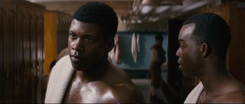 Movie still from “Race” (2016), directed by Stephen Hopkins – A man that is standing in a room; Close Up shot, Over the shoulder angle