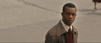 Movie still from “Race” (2016), directed by Stephen Hopkins – A man wearing a jacket and a red tie; Close Up shot, Over the shoulder angle