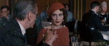 Movie still from “Race” (2016), directed by Stephen Hopkins – A woman wearing a red dress and a red hat; Close Up shot, Over the shoulder angle