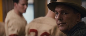 Movie still from “Race” (2016), directed by Stephen Hopkins – A baseball player wearing a hat; Close Up shot, Over the shoulder angle