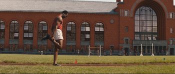 Movie still from “Race” (2016), directed by Stephen Hopkins – A man standing on a field with a red cone; Wide shot, Low angle
