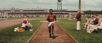 Movie still from “Race” (2016), directed by Stephen Hopkins – A man running on a track in front of a crowd; Wide shot, High angle