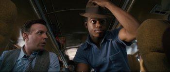 Movie still from “Race” (2016), directed by Stephen Hopkins – A man with a brown hat on a bus; Close Up shot, Over the shoulder angle