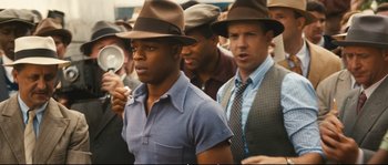 Movie still from “Race” (2016), directed by Stephen Hopkins – A group of men wearing hats and standing next to each other; Medium shot, Over the shoulder angle