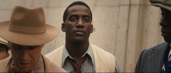 Movie still from “Race” (2016), directed by Stephen Hopkins – A person wearing a neck tie; Close Up shot, Over the shoulder angle