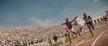 Movie still from “Race” (2016), directed by Stephen Hopkins – A man running on a track in front of a crowd; Extreme Wide shot, High angle