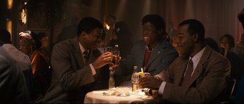 Movie still from “Race” (2016), directed by Stephen Hopkins – A group of men sitting at a table with drinks; Medium shot, High angle