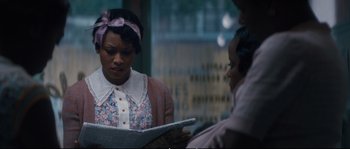 Movie still from “Race” (2016), directed by Stephen Hopkins – A woman reading a newspaper while another woman looks on; Medium shot, Over the shoulder angle