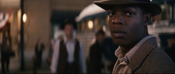 Movie still from “Race” (2016), directed by Stephen Hopkins – A person wearing a hat; Close Up shot, Over the shoulder angle