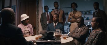 Movie still from “Race” (2016), directed by Stephen Hopkins – A group of people sitting around a table with drinks; Medium shot, High angle