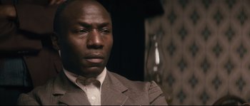 Movie still from “Race” (2016), directed by Stephen Hopkins – A person wearing a suit and tie; Close Up shot, High angle