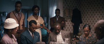 Movie still from “Race” (2016), directed by Stephen Hopkins – A group of people sitting around a table; Medium shot, Over the shoulder angle