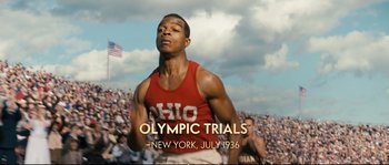 Movie still from “Race” (2016), directed by Stephen Hopkins – A man running in front of a crowd of people; Medium shot, High angle