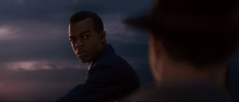Movie still from “Race” (2016), directed by Stephen Hopkins – A man is looking into a mirror at dusk; Close Up shot, Over the shoulder angle