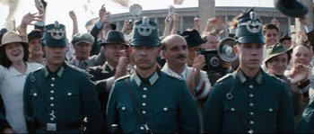 Movie still from “Race” (2016), directed by Stephen Hopkins – A group of people in hats and uniforms; Medium shot, Over the shoulder angle