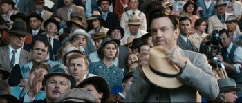 Movie still from “Race” (2016), directed by Stephen Hopkins – A crowd of people wearing hats in a room; Close Up shot, Over the shoulder angle