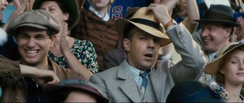 Movie still from “Race” (2016), directed by Stephen Hopkins – A man wearing a suit and a hat in a crowd of people; Close Up shot, Over the shoulder angle