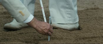 Movie still from “Race” (2016), directed by Stephen Hopkins – A man is holding a measuring stick in the sand; Extreme Close Up shot, High angle